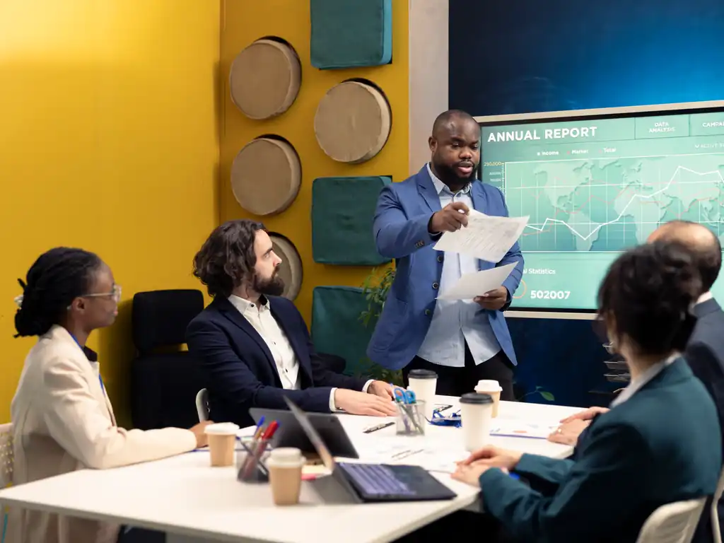 A diverse team of business professionals presenting an annual report in a modern boardroom.